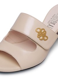 Sandalo scivoloso in pelle beige con punta aperta, design con ritagli e un accento dorato a motivo intrecciato sulla fascia superiore.