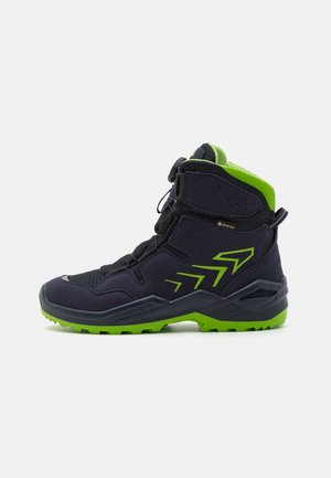 Stivale da esterno nero e verde con design a caviglia alta, parte superiore testurizzata, logo Gore-Tex e suola robusta per trazione.