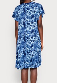 Šaty s krátkým rukávem v modrém tie-dye vzoru, polodlouhé a volného střihu, vyrobené z měkké látky. Mají volánkové rukávy a kulatý výstřih.