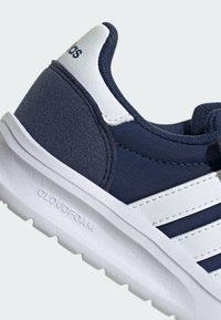 Baskets bleu marine avec une tige texturée, des accents en cuir blanc et une semelle extérieure en caoutchouc blanc avec "CLOUDFOAM" gravé.