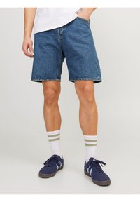 Denim shorts in a medium blue wash, featuring a relaxed fit, rolled cuffs, and classic five-pocket design. Paired with white-striped socks and navy sneakers.