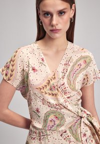 Cremfarbener Wickelkleid mit kurzen Ärmeln, das florale und paisley Muster in Rosa, Grün und dezenten Punkten zeigt; mit gebundenem Taillendetail.