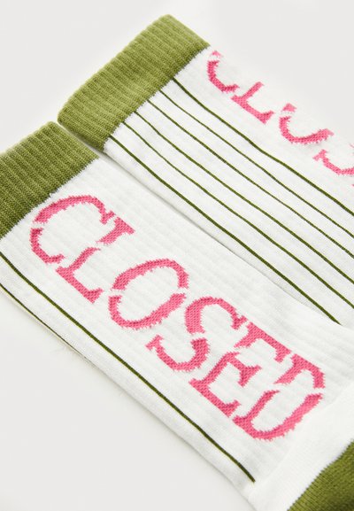 Calze a maglia con corpo bianco, testo "CLOSED" rosa e polsini a coste verdi. Sottilli strisce verdi corrono lungo i lati.