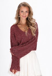 Pleteno bordo sv sweater s V-izrezom, ohlapnim krojem in dolgimi zvonastimi rokavi. Teksturna tkanina z diskretnim sijajem. V kombinaciji z belimi krili.