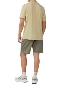 Jasnożółta koszulka z krótkim rękawem, zielone szorty, szare buty sportowe, białe skarpetki w paski. Prosty design, swobodny krój.