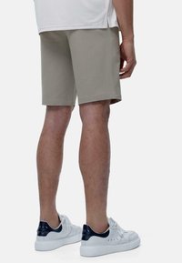 Shorts en mélange de coton beige avec une coupe droite, longueur genou, ourlet sans couture et poches latérales, accompagnés de baskets blanches avec des accents navy.