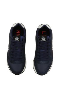 Scarpe da ginnastica blu navy con una combinazione di materiali lisci e testurizzati. Accenti bianchi sulla suola e sui loghi, con la scritta "CORRI PIÙ VELOCEMENTE DI QUANTO PUOI" sulla linguetta.