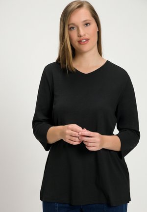 Zwarte V-hals shirt met driekwart mouwen; gemaakt van gladde stof, heeft een ontspannen pasvorm en een nette zoom. Geen zichtbare patronen of hardware.