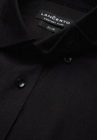 Czarna, wąska koszula z teksturowanej tkaniny, z kołnierzykiem w szpic, czarnymi guzikami i metką z napisem "LANCERTO COMFORT PLUS".