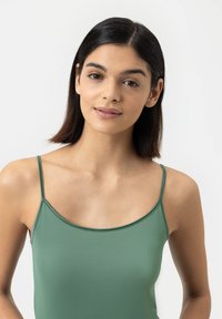 Groene mouwloze top met een gladde textuur en verstelbare dunne bandjes, voorzien van een ronde halslijn en een aansluitend ontwerp.