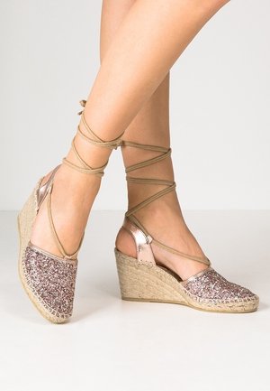 Vinkelsandaler med et glitrende pink stofoverdel, beige flettet jutesål og krydsende brune ankelremme for en sikker pasform.