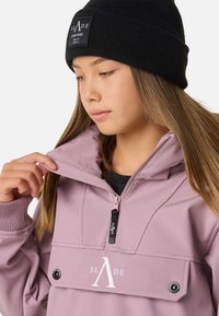 Jasnoróżowa bluza z kapturem i suwakiem przy szyi, z dużą przednią kieszenią i białym logo. W komplecie z czarną prążkowaną czapką beanie.