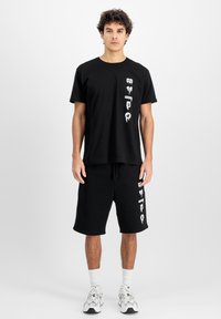Sort bomulds t-shirt og shorts sæt med hvide grafiske designs. T-shirten har en afslappet pasform, shortsene er over knæet med en elastisk talje.