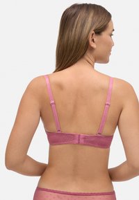 Sujetador de encaje rosa con tirantes ajustables, patrón de puntos y cierre de gancho en la parte posterior. Textura suave y soporte medio.