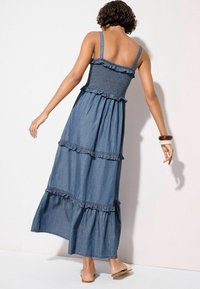 Denimmaxiklänning med spagettiband, smockad byst, lager på lager-volanger och subtil textur. Ljusblå färg med en flödande silhuett.