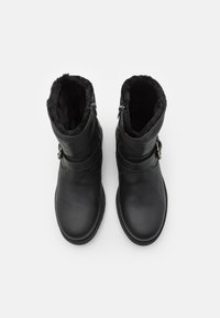 Schwarze Stiefeletten aus Kunstleder mit strukturiertem Finish, Futter aus Fell und seitlichem Reißverschluss. Verfügt über einen Riemen und eine Metall-Schnallenakzent.