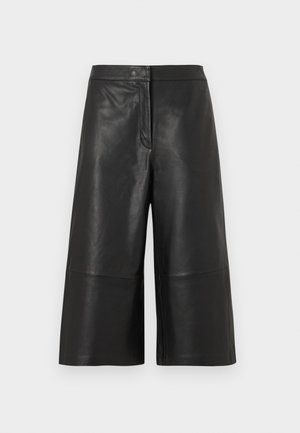 Shorts culotte en cuir noir à taille haute, jambes larges et texture lisse. Dotés d'une fermeture avant avec bouton et zip, avec un minimum de détails.