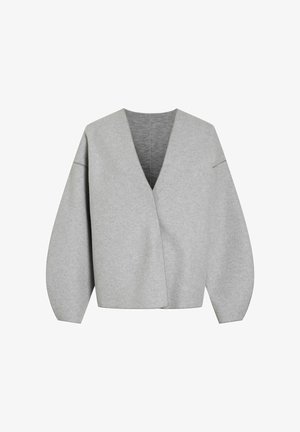 Pull à enfiler gris avec un col en V plongeant, des manches ballon surdimensionnées et un tissu texturé. Présente des détails cousus le long des bords.