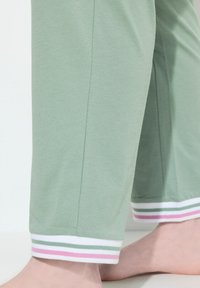 Mintgrüne Hose mit lockerem Schnitt, mit mehrfarbigen gestreiften Bündchen in Rosa, Grün und Weiß, aus weichem, bequemem Stoff.