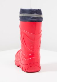 Rode waterdichte rubberen laars met een marineblauwe stoffen manchetkraag en een reflecterende streep aan de bovenkant. Voorzien van gestructureerde zijkanten en een robuust zool voor grip.