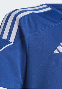 Camiseta deportiva azul hecha de tela transpirable; presenta rayas horizontales blancas en los hombros y un pequeño logo en la parte frontal.