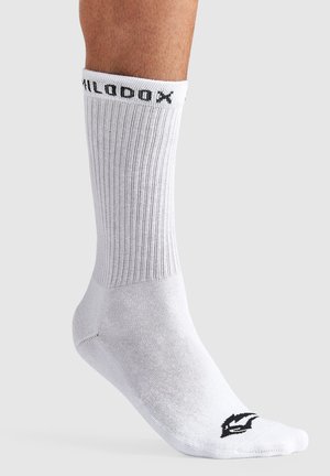 Hvide sportsstrømper med lodret ribbning, sort logo ved kanten og på tæerne, midt på læggen, fremstillet af et åndbart materiale.