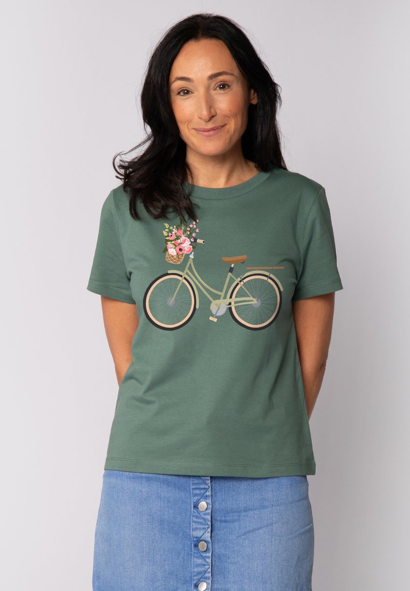 T-shirt en coton vert avec un graphisme de bicyclette portant un panier de fleurs. Manches courtes et col rond. Texture lisse, coupe décontractée.