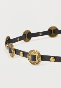 Μαύρη δερμάτινη ζώνη με κυκλικά μεταλλικά διακοσμητικά στοιχεία χαραγμένα με μοτίβα αστεριών και τετραγώνων. Λεία υφή με διακοσμητικά κουμπιά.