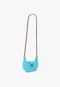 Una piccola borsa curva in pelle blu brillante con una tracolla in metallo dorato e un dettaglio di chiusura circolare. Texture liscia.
