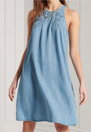 Lichtblauwe denimjurk met een losse pasvorm, mouwloos ontwerp, geborduurde bloemenaccenten bij de halslijn en een afgeronde zoom.