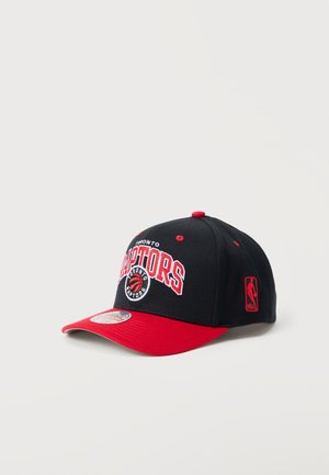 Sort og rød Toronto Raptors NBA kasket med holdlogo foran og NBA-logo på siden, vist på hvid baggrund.