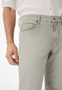 Pantaloni in denim grigio chiaro, slim fit, con frontale piatto, cinque tasche e cuciture a contrasto intorno alla vita e alle tasche.