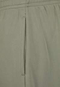 Light green breathable athletic shorts featuring a textured mesh fabric with a side pocket and an elastic waistband design.