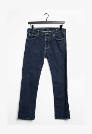 Tmavě modré džínové kalhoty s rovnýcm střihem, pěti kapsami, prošívanými detaily a zapínáním na knoflík. Visí na černém háčku.