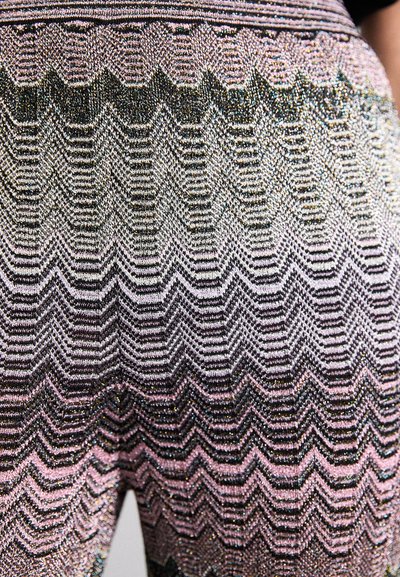 Leggings s uzorkom koji prikazuje zigzag dizajn u metalik nijansama crne, ružičaste i srebrne boje. Tekstura je glatka s blagim sjajem.