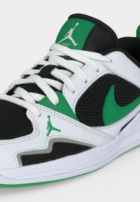 Λευκό, μαύρο και πράσινο αθλητικό παπούτσι με λευκά κορδόνια, πράσινο λογότυπο Nike Swoosh και πράσινα λογότυπα Jumpman στο πλάι και στη γλώσσα.