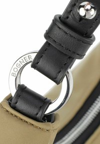 Zwarte leren riem met een zilveren metalen ring, bevestigd aan een gestreepte beige stoffen tas, met een zwarte rits en grijze voering.
