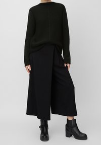 Mörkgrön stickad tröja med en avslappnad passform, matchad med svarta vida byxor. Svarta ankelboots med tjock sula och en remaccent.