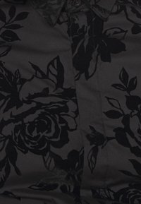 Zwarte stoffen shirt met een fluwelen bloemenpatroon in verschillende tinten zwart. Inclusief een klassieke kraag en knoopdetails.
