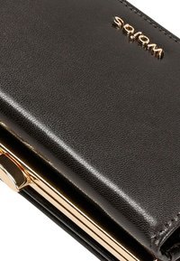 Černá texturovaná peněženka s hladkým povrchem, vybavená zlatým kovovým zapínáním a raženým logem, kompaktní obdélníkový tvar.