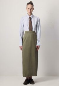 Lichtblauw shirt met kraag, bruine met patroon gevulde stropdas, olijfgroene hoge taille rok en donkerbruine schoenen, allemaal in een formele stijl gecombineerd.