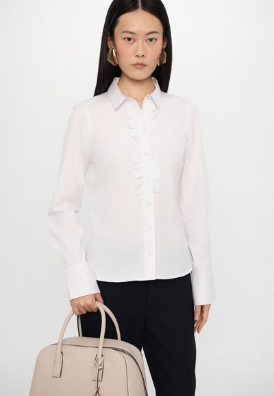 Witte blouse met gerimpelde voorkant, knoopsluiting, lange mouwen, en gecombineerd met een beige handtas. Glad materiaal, slim fit ontwerp.