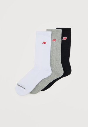 Tri para nogavic New Balance v bež, sivi in črni barvi, vsaka z rdečim logotipom "NB" blizu zgornjega roba.