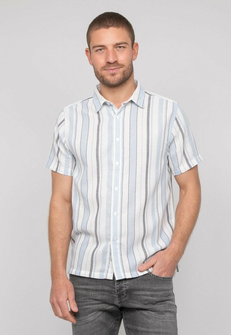 Chemise à manches courtes bleu clair avec des rayures verticales, dotée de boutons et d'un col. Le tissu a une finition texturée.