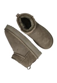 Tan suede enkellaarsjes met een zachte, fluffy voering, versterkte stiksels en een gestructureerde zool. Voorzien van een kleine lus aan de achterkant voor eenvoudig aan- en uittrekken.