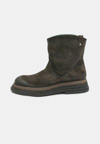 Stivale alla caviglia in suede marrone con punta rotonda, dettagli cuciti, un tacco leggero e una linguetta sul retro per una facile calzata.