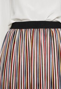 Jupe plissée à rayures verticales en rouge, noir, bleu, jaune et blanc, dotée d'une taille élastique noire et d'une texture lisse.