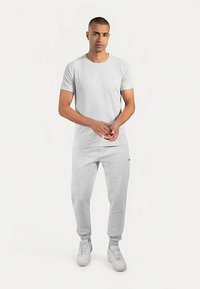 Grijs katoenen T-shirt en bijpassende joggers. Het T-shirt heeft een ronde hals, aansluitende mouwen en een klein logo. De joggers hebben een elastische tailleband.