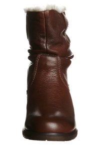 Botte d'hiver en cuir marron avec doublure en fourrure blanche douce au sommet, bout arrondi et semelle plate noire.