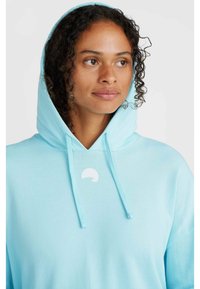 Light blue hoodie made of soft fabric, featuring a front pocket, drawstrings, and a small white logo on the chest.